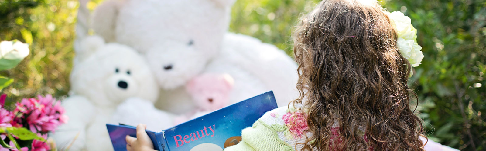 Girl reading a book to teddy bears 